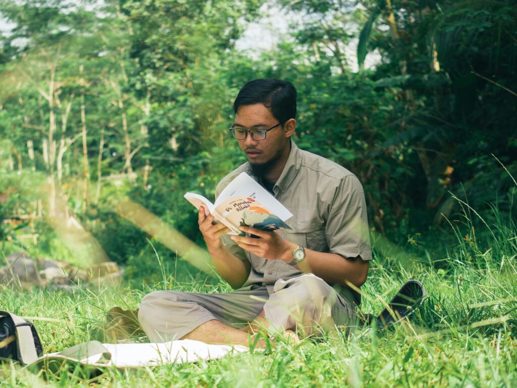 A man reading a book in a natural setting.
